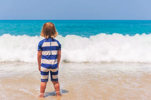 Adorable kid having fun on summer vacation, playing by the sea, back view,  image taken in Tropea, Calabria, Italy