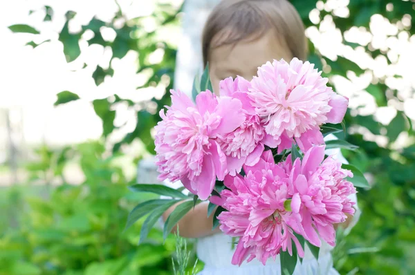 Little child presenting a bouquet of peony flowers