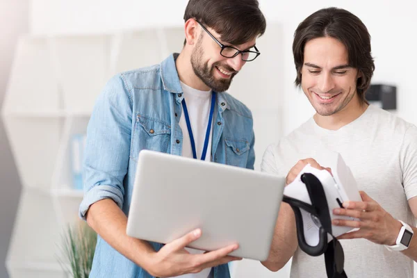 Positive smiling colleagues holding virtual reality glasses