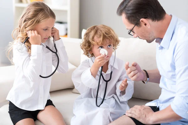 Children with stethoscopes treating father