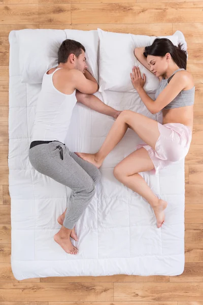 Young man and woman sleeping on bed