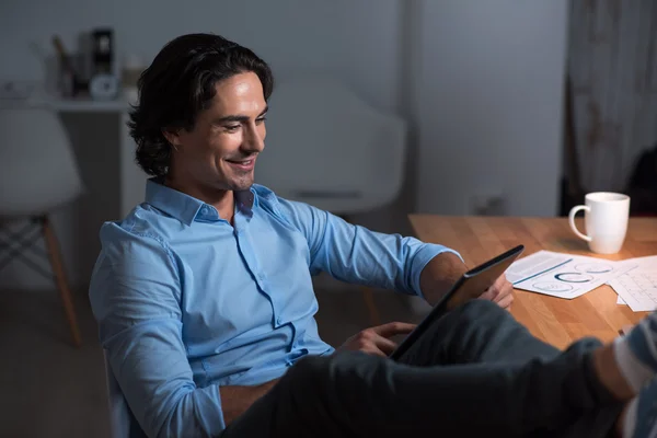 Smiling relaxed young man using tablet .