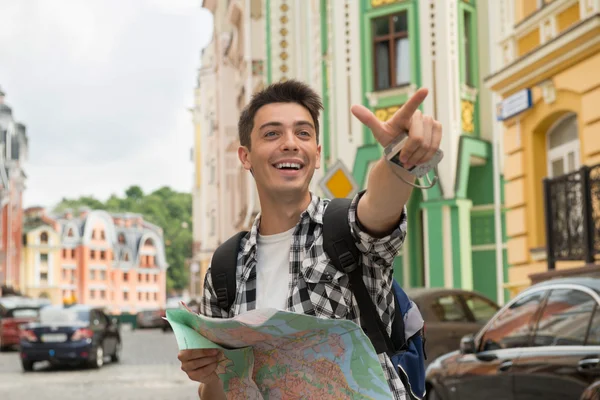 Male traveler holding a map and showing ahead