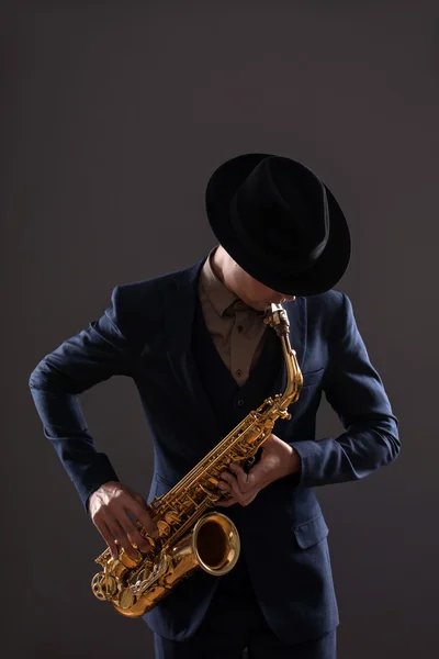 Portrait of a jazz man in a suit with a hat hiding his face and