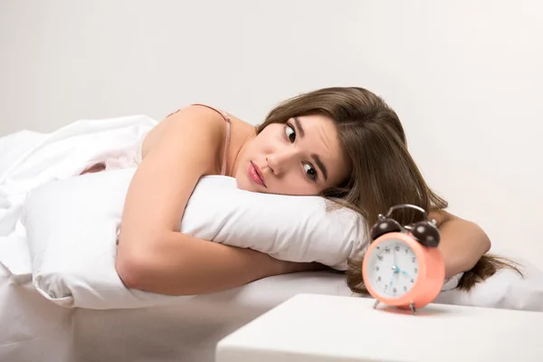 Beauty lying on the bed with a clock
