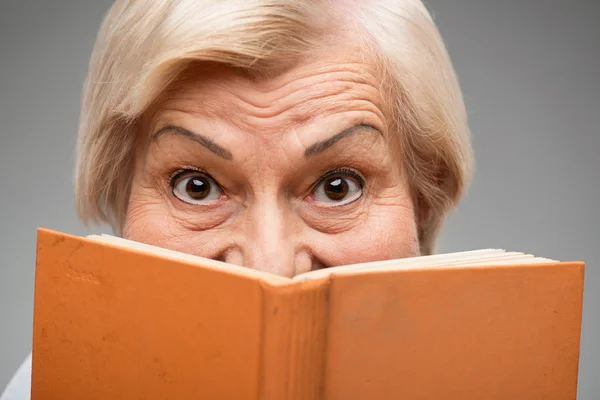 Elderly woman holding yellow book
