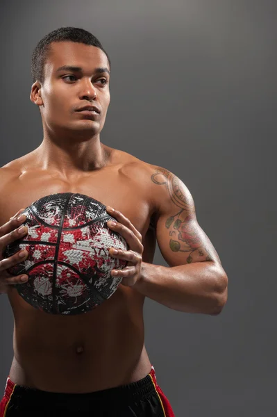 Young handsome African man posing shirtless with basketball ball