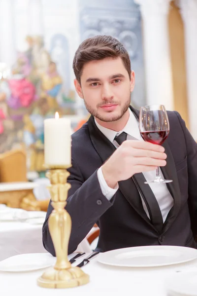 Man in suit raising his glass of wine