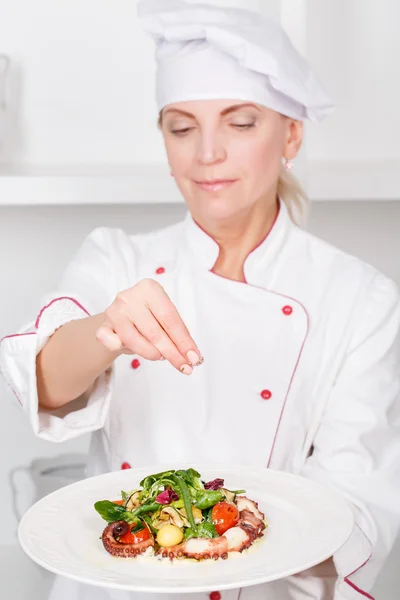 Chef-cook  sprinkling  salad with spices