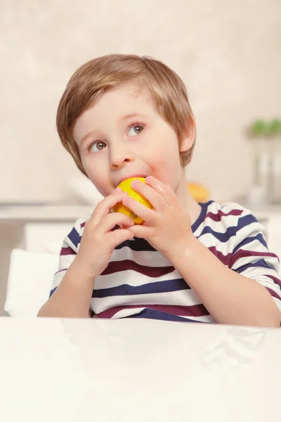 Kid biting piece of lemon