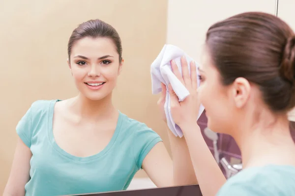 Beautiful lady cleaning mirror