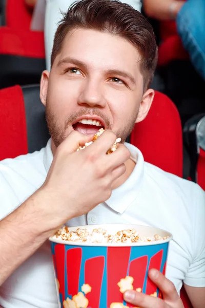 Man greedy eating popcorn in cinema.