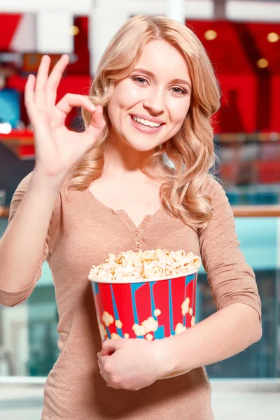 Woman with popcorn showing OK
