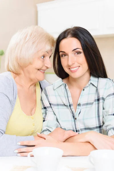 Grandmother and granddaughter sitting in kitchen