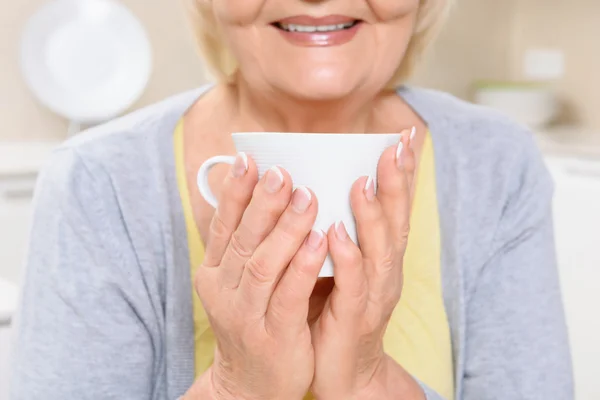Smiling old woman holding cup of tea