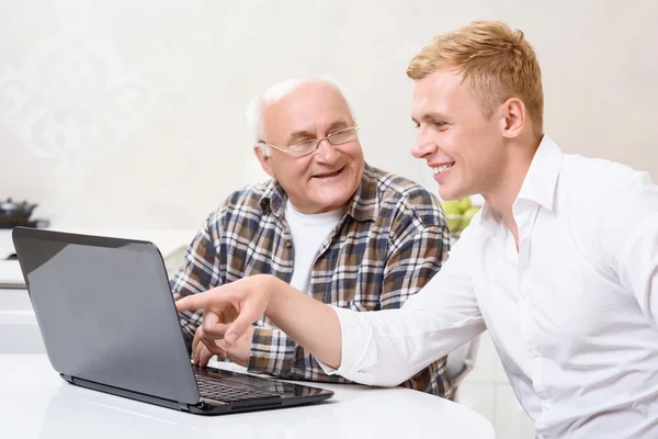 Grandfather and grandson sitting with laptop
