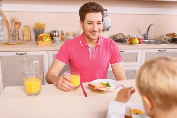 Loving dad watches his son eating.