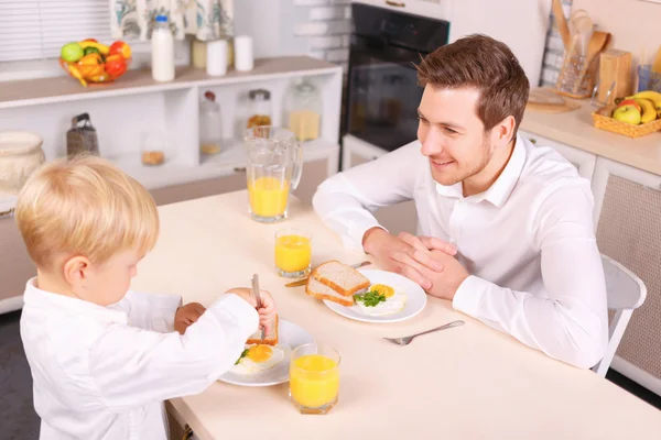 Attentive dad watches his son eating.