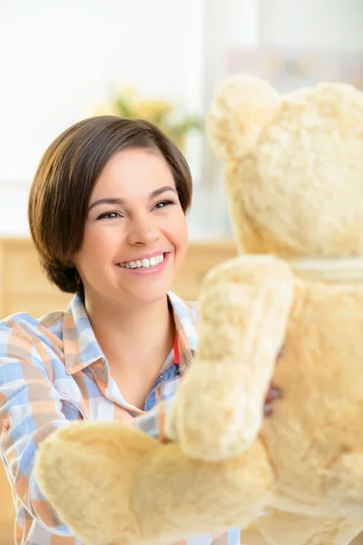 Teenage girl playing with teddy bear.
