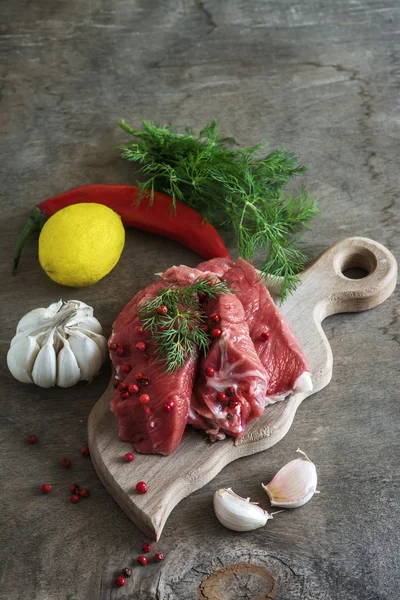 Raw lamb meat with spices on wood board over old wooden backgrou