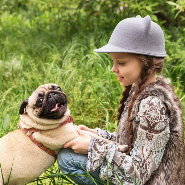 Little girl playing with her pug dog outdoors in rural areas