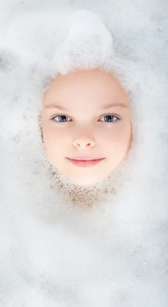 Delightful smiling face of a little girl in the foam