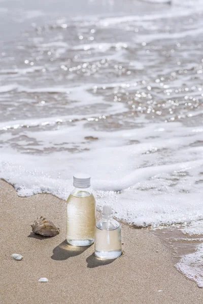 Bottles with oil essence and shell in the sea waves. Spa and wel