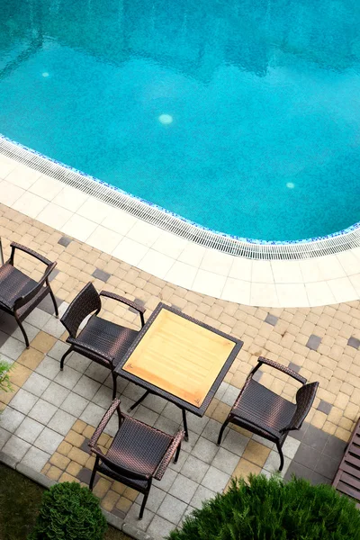 Empty rattan table and chairs next to the pool. Vacation and tra