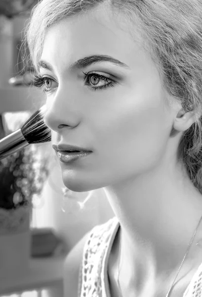 Make-up artist applying foundation powder or blush with makeup b