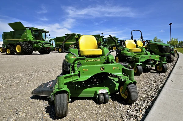 Row of John Deere combines and riding lawn mowers