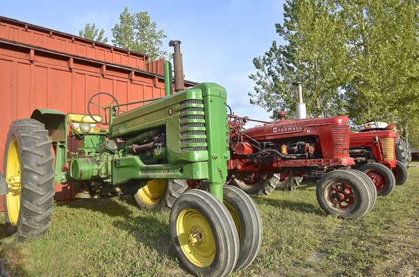 John Deere and Farmall tractors are lined up.