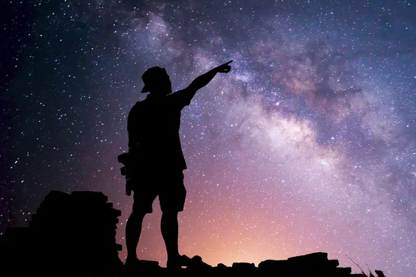 Star-catcher. A person is standing next to the Milky Way galaxy