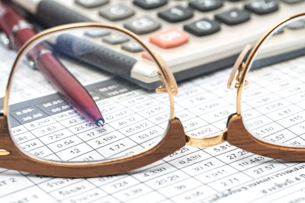 Glasses and calculator on business paper with calculations