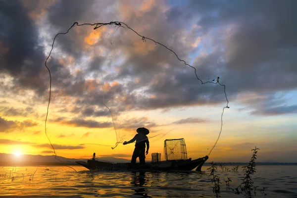 Silhouette of fisherman throwing fishing net
