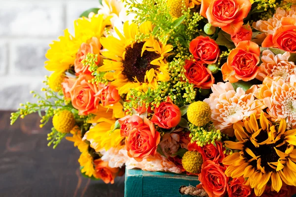 Colorful bouquet of flowers in turquoise box wooden table