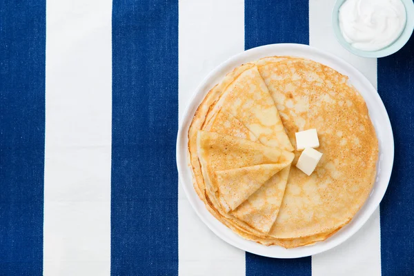 Thin crepes or pancakes with butter, honey and sour cream Top view Copy space
