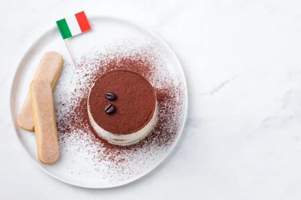Tiramisu, traditional Italian dessert on a white plate with Italian flag Top view Copy space
