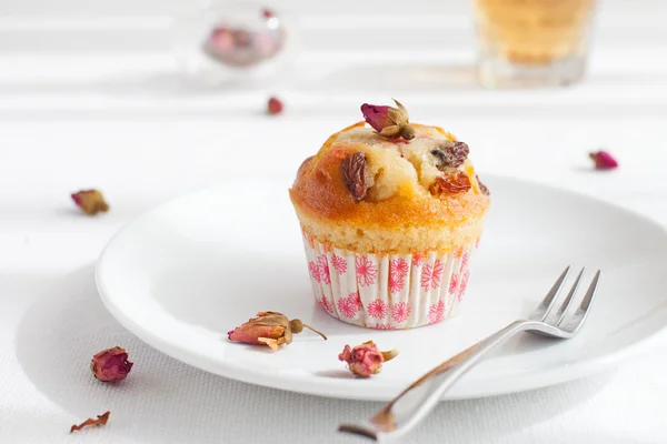 Muffin, mini cake, cup cake on a white plate with a rose buds tea