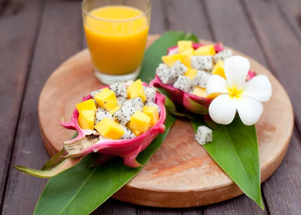 Tropical fruit salad in pitahaya, dragon bowls with mango juice.