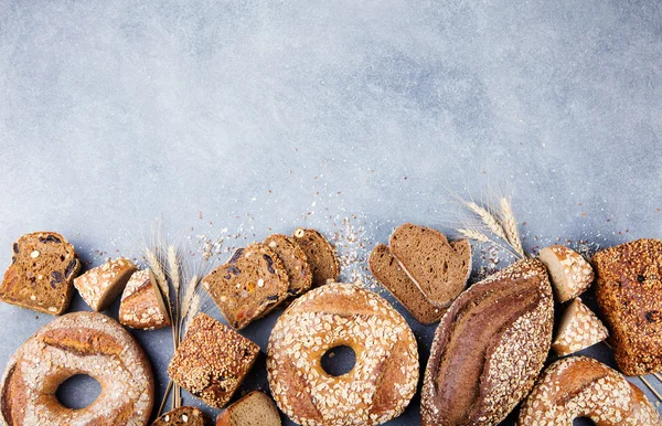 Assortment of baked bread on stone table background Composition with bread slices and rolls Copy space