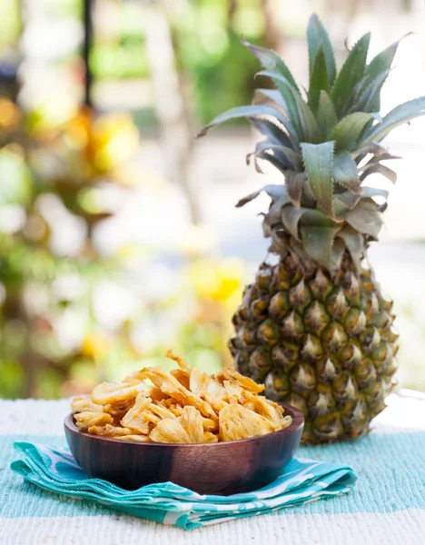 Dried dehydrated deep fried pineapple chips in a wooden bowl on a textile background