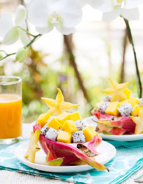 Tropical fruit salad in pitahaya, mango, dragon fruit bowls with a glass of juice Diet, healthy fruit salad Healthy breakfast, weight loss concept