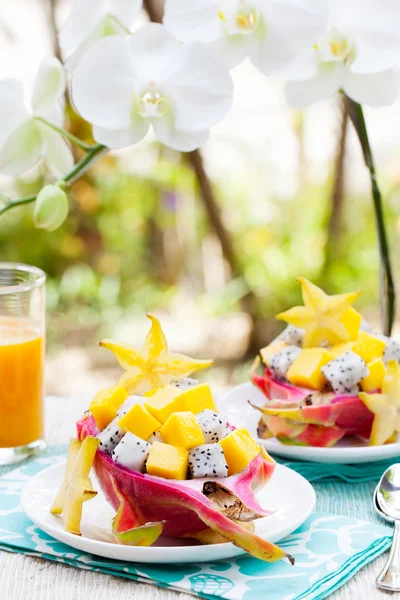 Tropical fruit salad in pitahaya, mango, dragon fruit bowls with a glass of juice Diet, healthy fruit salad Healthy breakfast, weight loss concept