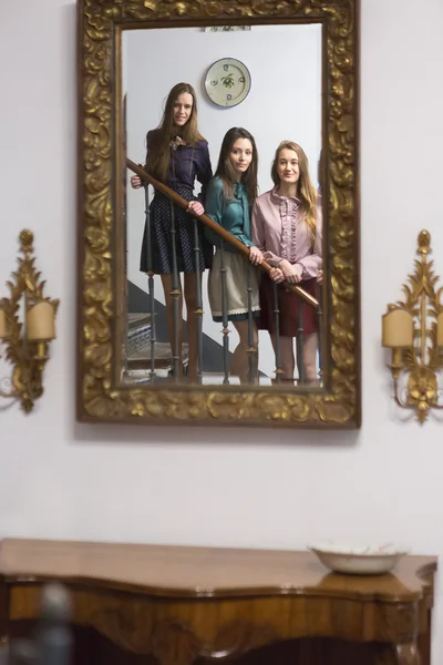 Three women on steps looking in mirror