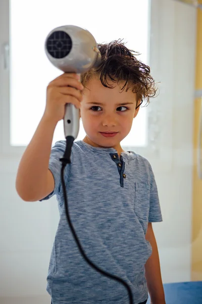 Boy blowing his hair with hair dryer