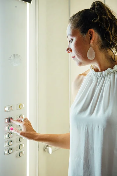 Adult woman push the button inside an elevator