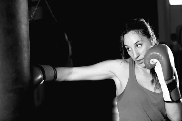 Female boxer practicing strokes on punching bag