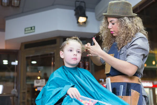 Woman in hat cutting boy hair