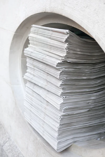 Many newspapers stacked in a pile.