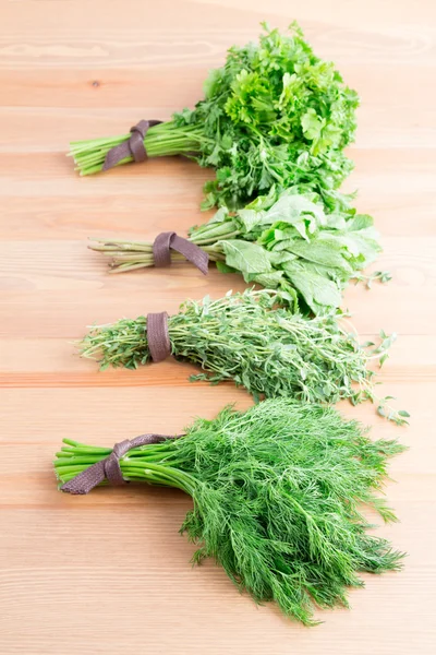 Bunches of fresh dill,  thyme, mint and parsley on a light woode